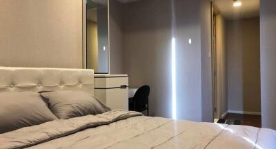 Modern bedroom with neutral tones, tufted headboard, and hallway view