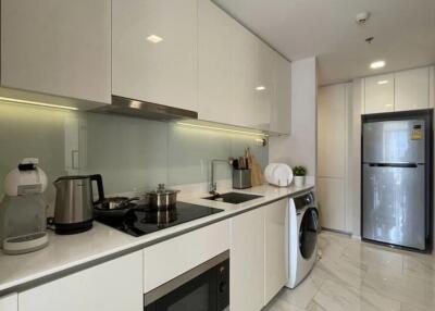 Modern kitchen with sleek white cabinetry, built-in appliances, and a washing machine