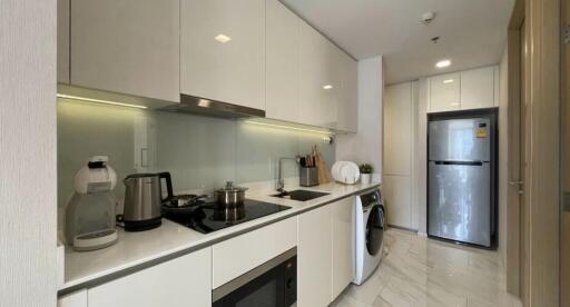 Modern kitchen with white cabinetry, appliances, and washer