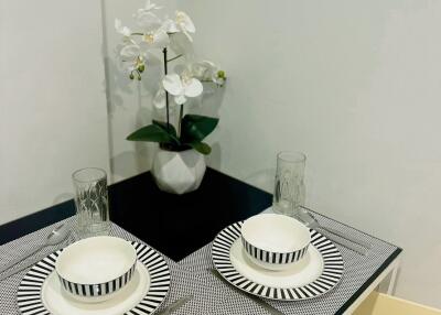 Small dining table setup with plates, glasses, and a potted plant