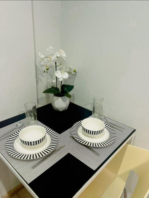 Small dining table setup with plates, glasses, and a potted plant