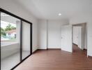 Spacious bedroom with wooden flooring and access to a balcony