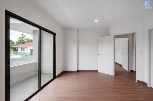 Spacious bedroom with wooden flooring and access to a balcony