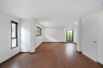 Spacious, unfurnished living area with wooden floors and large windows