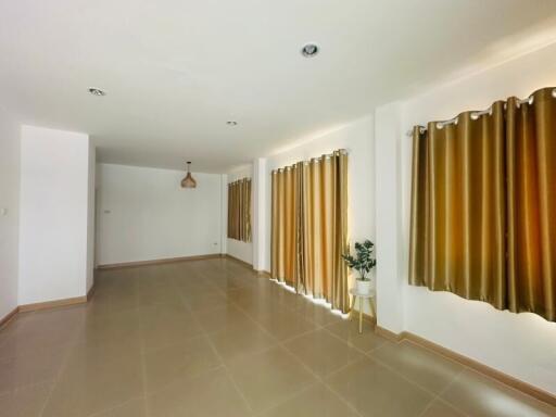 Spacious living room with large windows and brown curtains