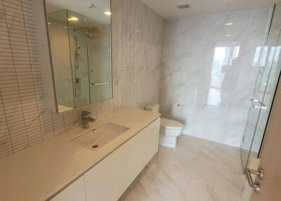 Modern bathroom with large mirror, sink, toilet, and shower