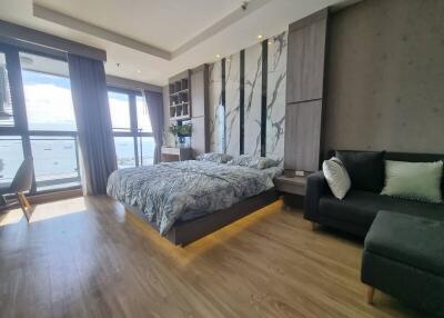 Modern bedroom with large windows, bed, sofa, and wooden flooring