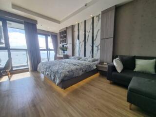 Modern bedroom with large windows, bed, sofa, and wooden flooring