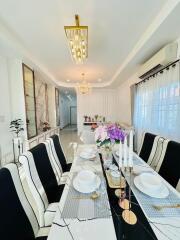 Elegant dining area with modern table setting, chandelier lighting, and large windows.