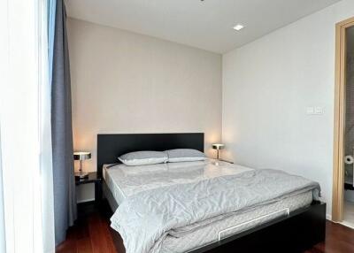 Modern bedroom with double bed, nightstands, lamps, and an en-suite bathroom