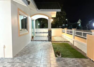 Exterior view of a modern house at night with a tiled patio and garden area