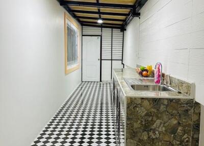 Narrow kitchen with checkered floor and stone countertop