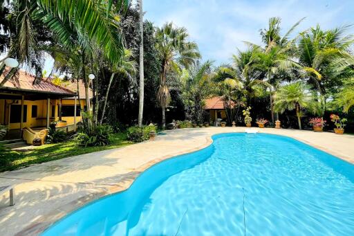 A spacious outdoor area featuring a swimming pool surrounded by trees and greenery