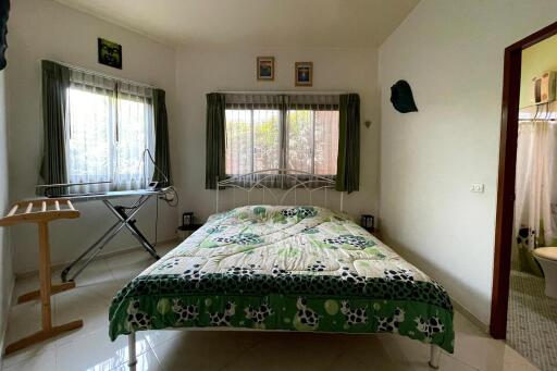 Bedroom with large windows, iron board, and covered bed