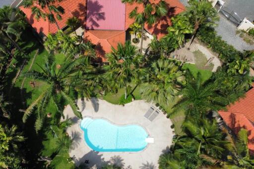 Aerial view of a property with a swimming pool and lush landscaping