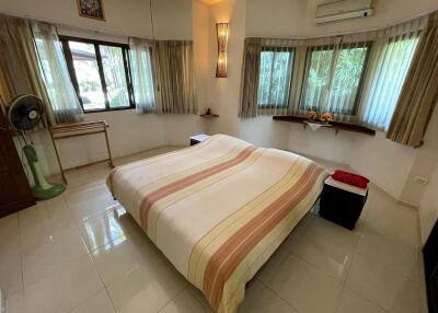 Cozy bedroom with a large bed, windows with curtains, air conditioning, and tiled floor