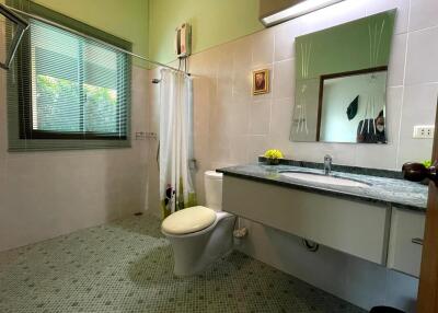 Modern bathroom with green tones, featuring a large window, vanity with sink, toilet, and walk-in shower