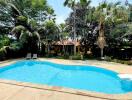 Outdoor swimming pool with surrounding trees and lounge chairs