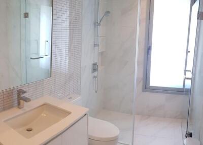 Modern white bathroom with glass shower, sink, and toilet