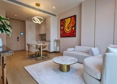 Modern living room with a minimalist design featuring a white sofa, coffee table, wall art, and dining area