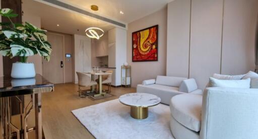 Modern living room with a minimalist design featuring a white sofa, coffee table, wall art, and dining area