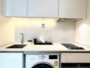 Modern kitchen with white cabinets, stove, sink, dishwasher, and washing machine