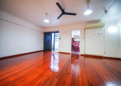 Spacious living room with polished wooden flooring, ceiling fan, and modern lighting fixtures.