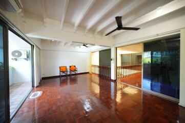 Spacious living room with polished wooden floors and ceiling fan