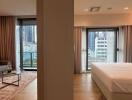 A photo of a modern bedroom adjoining a living area with large windows and city views