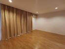 Spacious living room with wooden flooring and window curtains