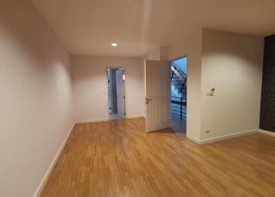 Empty bedroom with wooden flooring and a door leading to another room.