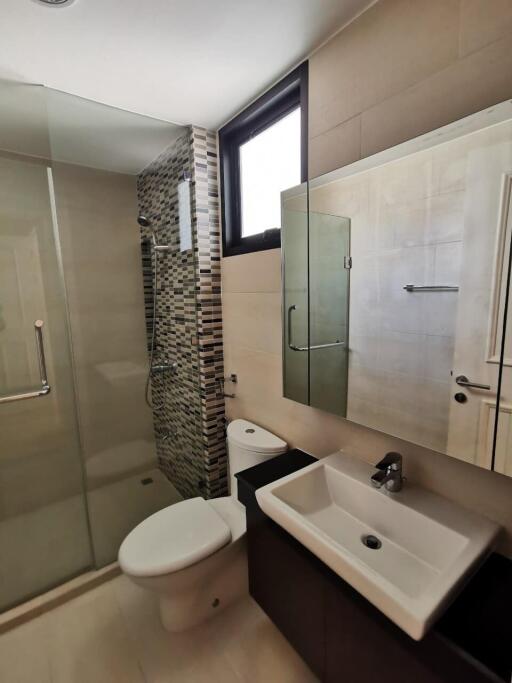 Modern bathroom with glass shower, window, and vanity