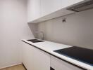 Modern kitchen with white cabinetry, built-in cooktop, and sink