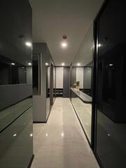 Well-lit modern hallway with sleek glass and dark paneling