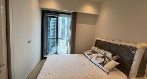 Cozy bedroom with a bed and a window with a view of tall buildings