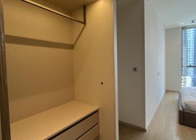 Photo of a bedroom with an empty closet and a view of the bed near the window.