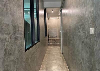 Modern concrete-finished hallway with large window and stairs leading to the next floor