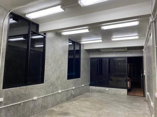 Room with concrete walls and ceiling, large windows, and fluorescent lighting