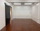 Empty room with wooden parquet flooring and a black sliding glass door