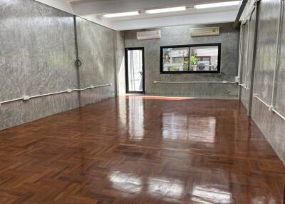Spacious empty room with wooden floor, large windows, and air conditioning units