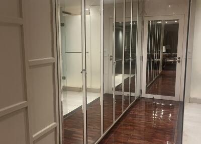 A hallway with mirrored closet doors and wooden flooring
