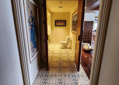 hallway leading to a bathroom with tiled floor and open wooden doors