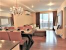 Well-lit living room with a chandelier, dining area, and balcony access