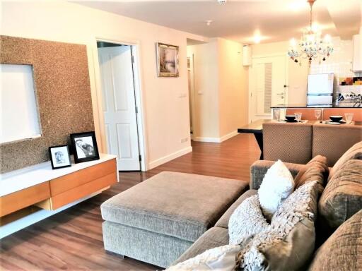 Modern living room with beige sofa, coffee table, and open view to kitchen