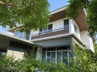 Modern two-story house exterior with lush greenery