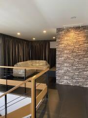 Modern living room with large windows, blackout curtains, stone accent wall, and sleek railings