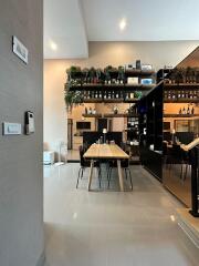 Modern dining room with wooden table and chairs, shelf with plants and decor, and high ceiling