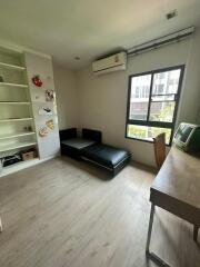 spacious living room with a black sectional sofa, desk, and shelves