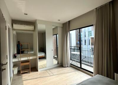 Bright bedroom with large windows and balcony access, mirrored closet, and wooden flooring.