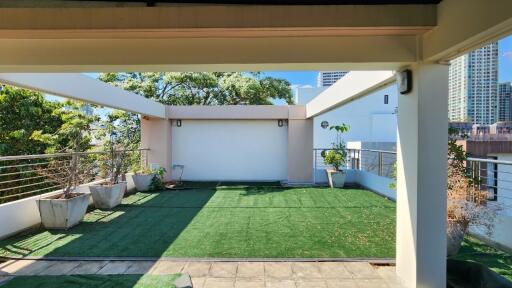 Spacious outdoor terrace with artificial grass and potted plants